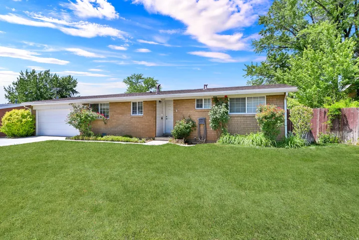 Brick exterior ranch home featuring a two-car garage, white trim, and a front lawn with established landscaping