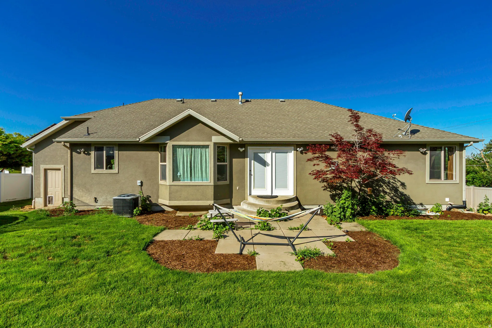 Rear exterior featuring stucco siding, a bay window, and a white double door