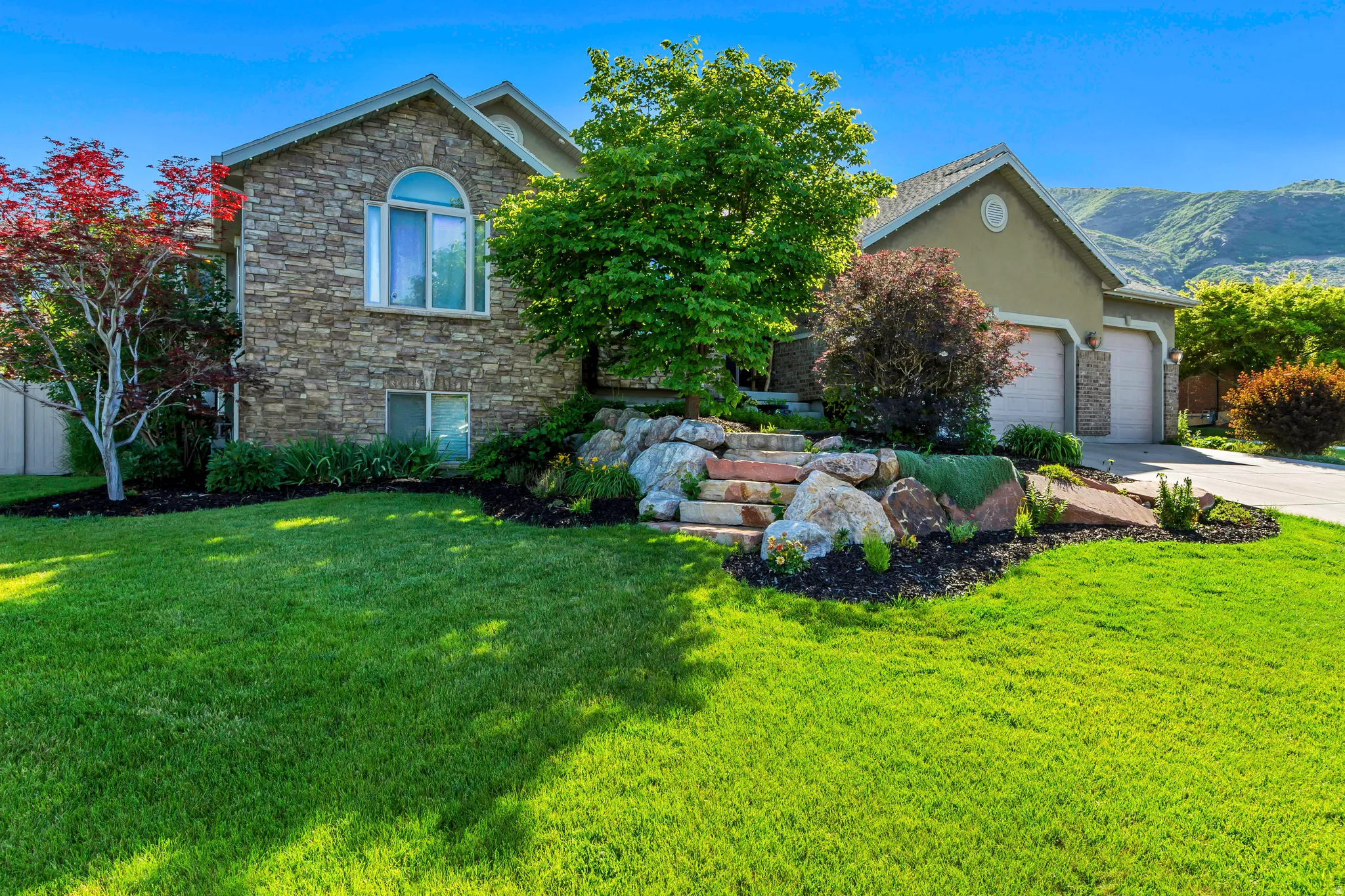 Stone facade residence featuring an arched window and an attached multi-car garage with stone accents