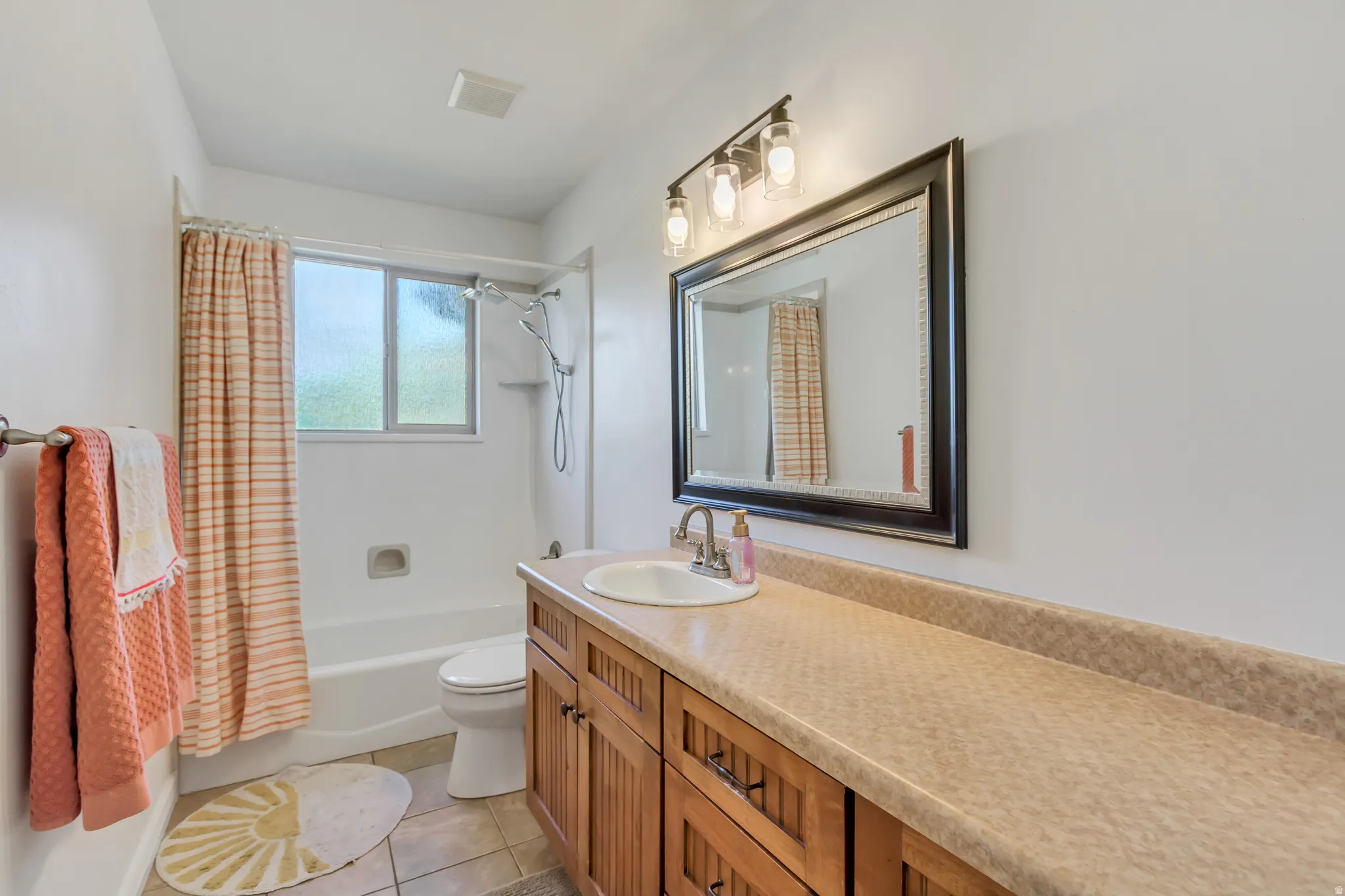 Bathroom featuring a comprehensive vanity with a single basin sink, wood-finish cabinetry, and an extended countertop