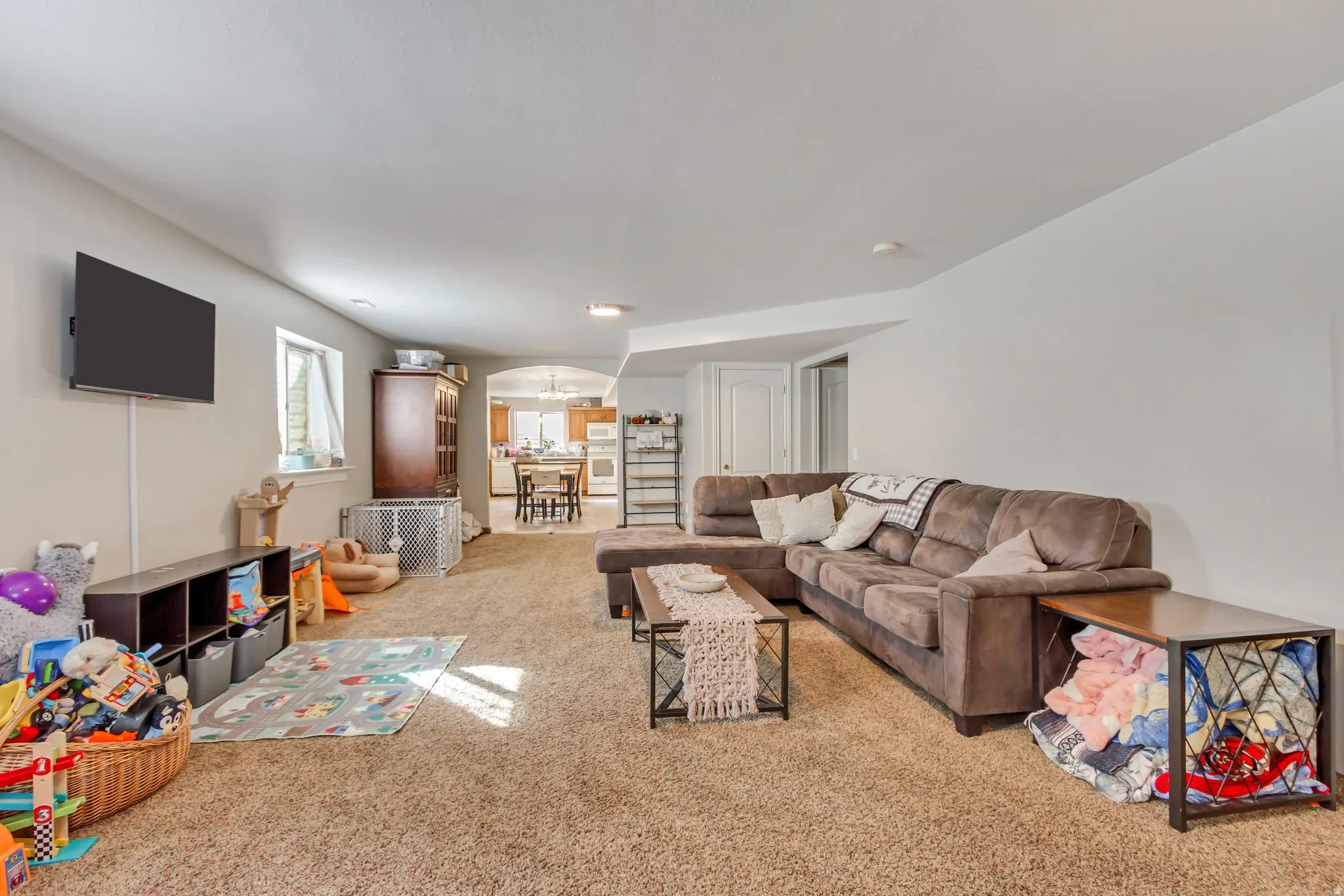 Spacious lower-level living area featuring neutral carpeting, recessed lighting, and white walls