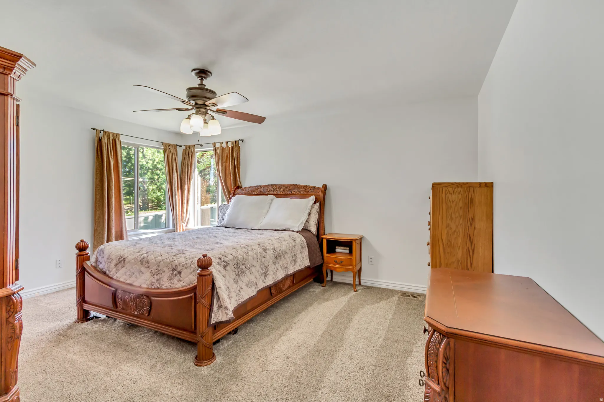 Spacious room featuring a bay window, ceiling fan, and neutral carpet flooring