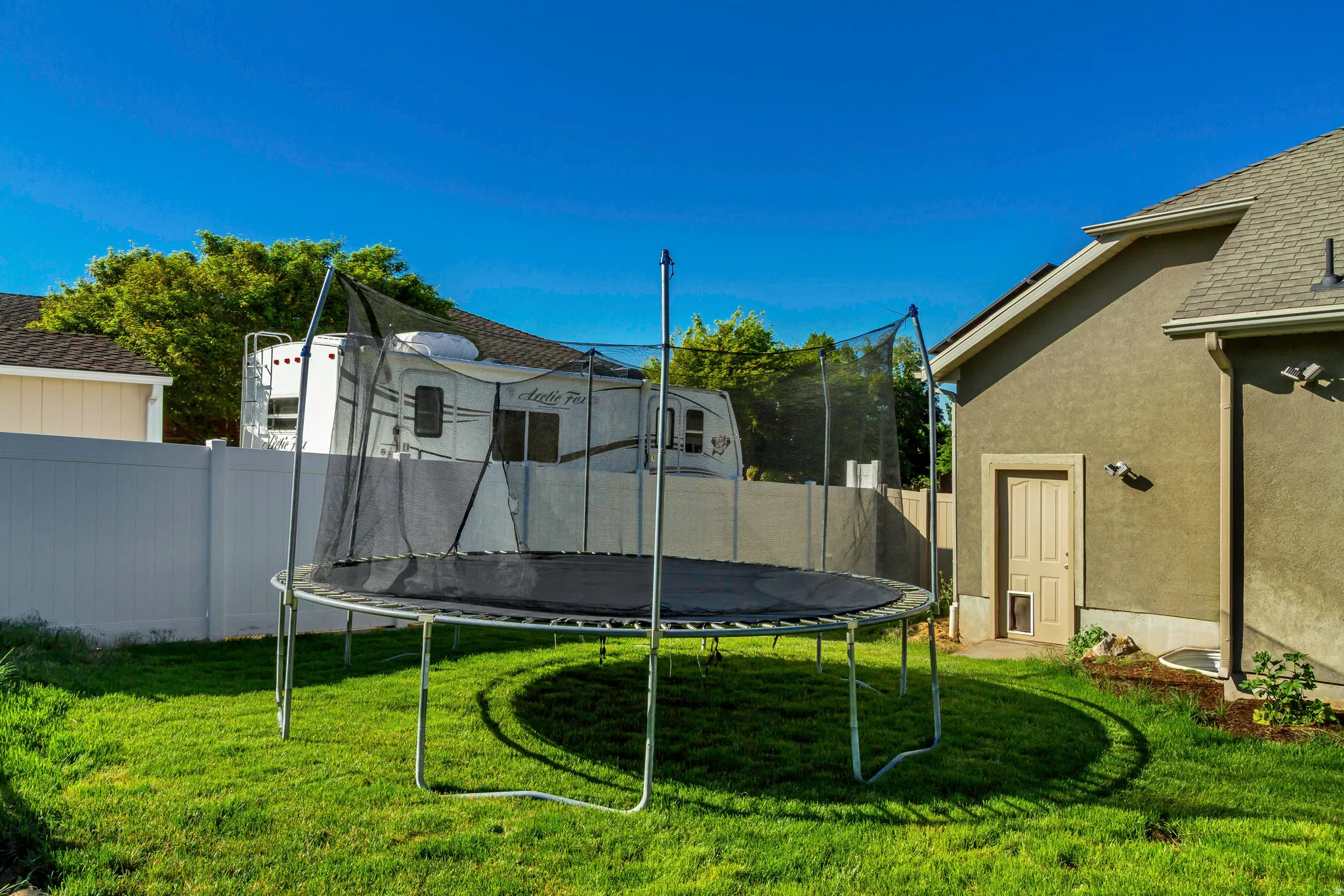 Expansive backyard featuring a lush green lawn, a stucco exterior, and a privacy fence