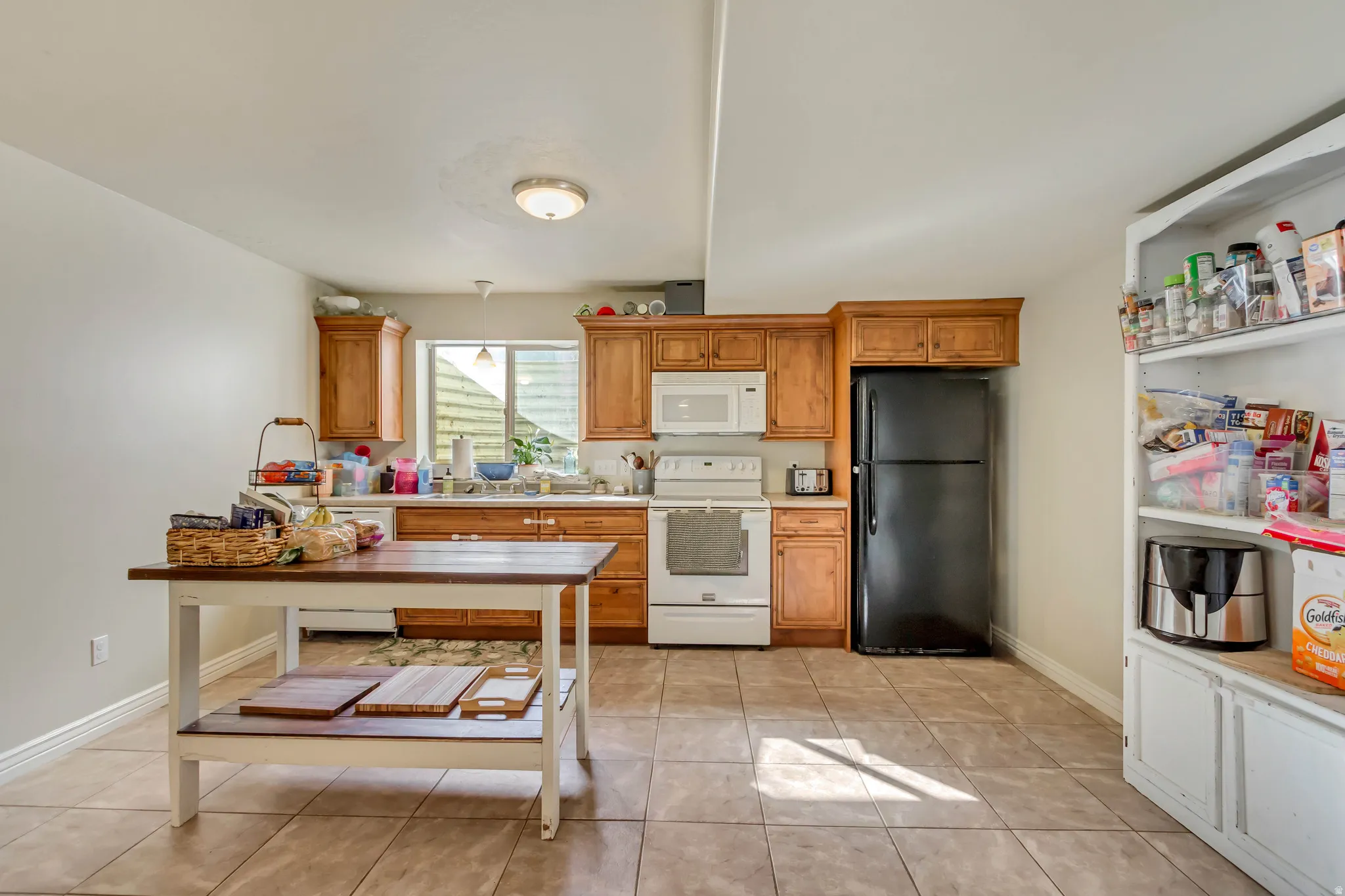 Kitchen featuring wood cabinetry, white appliances, and a black refrigerator