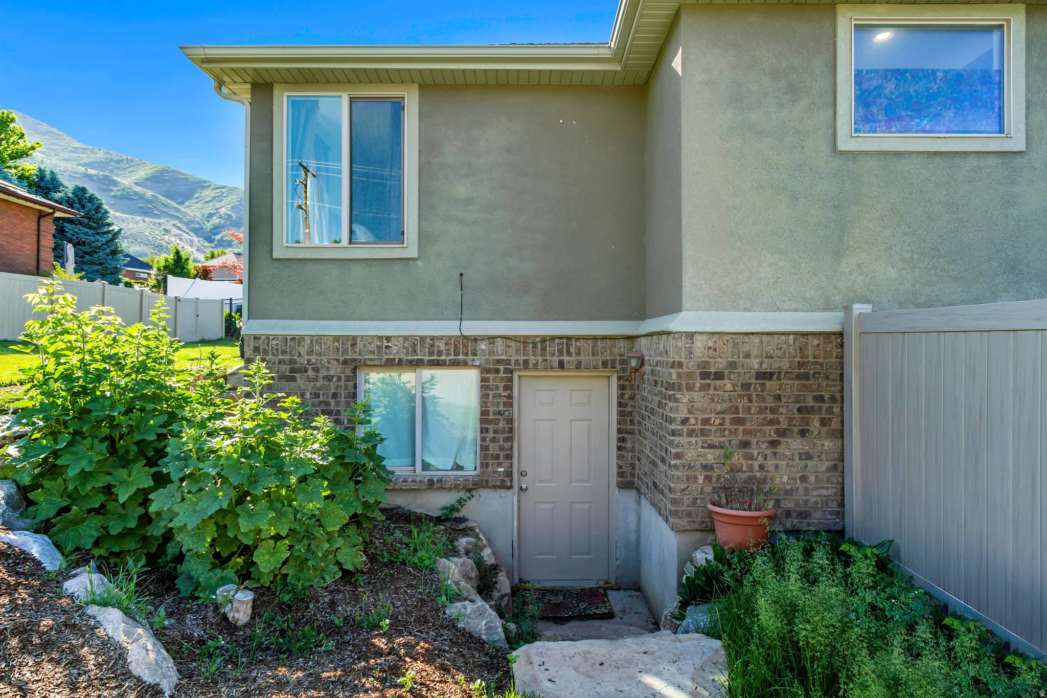Stucco and brick exterior with multiple windows and a private entry door