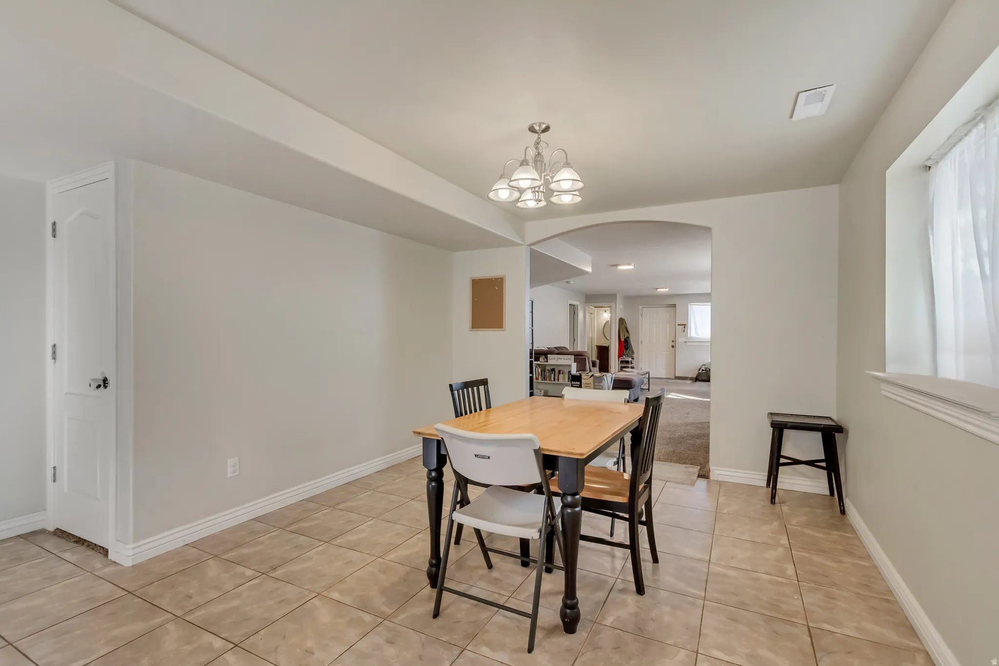 Tiled flooring extending into an archway, featuring a built-in storage cabinet with a white paneled door