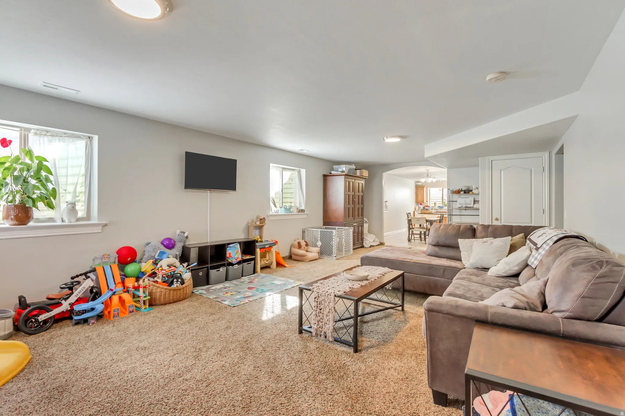 Carpeted recreation room featuring recessed lighting, a mounted wall screen, and multiple windows