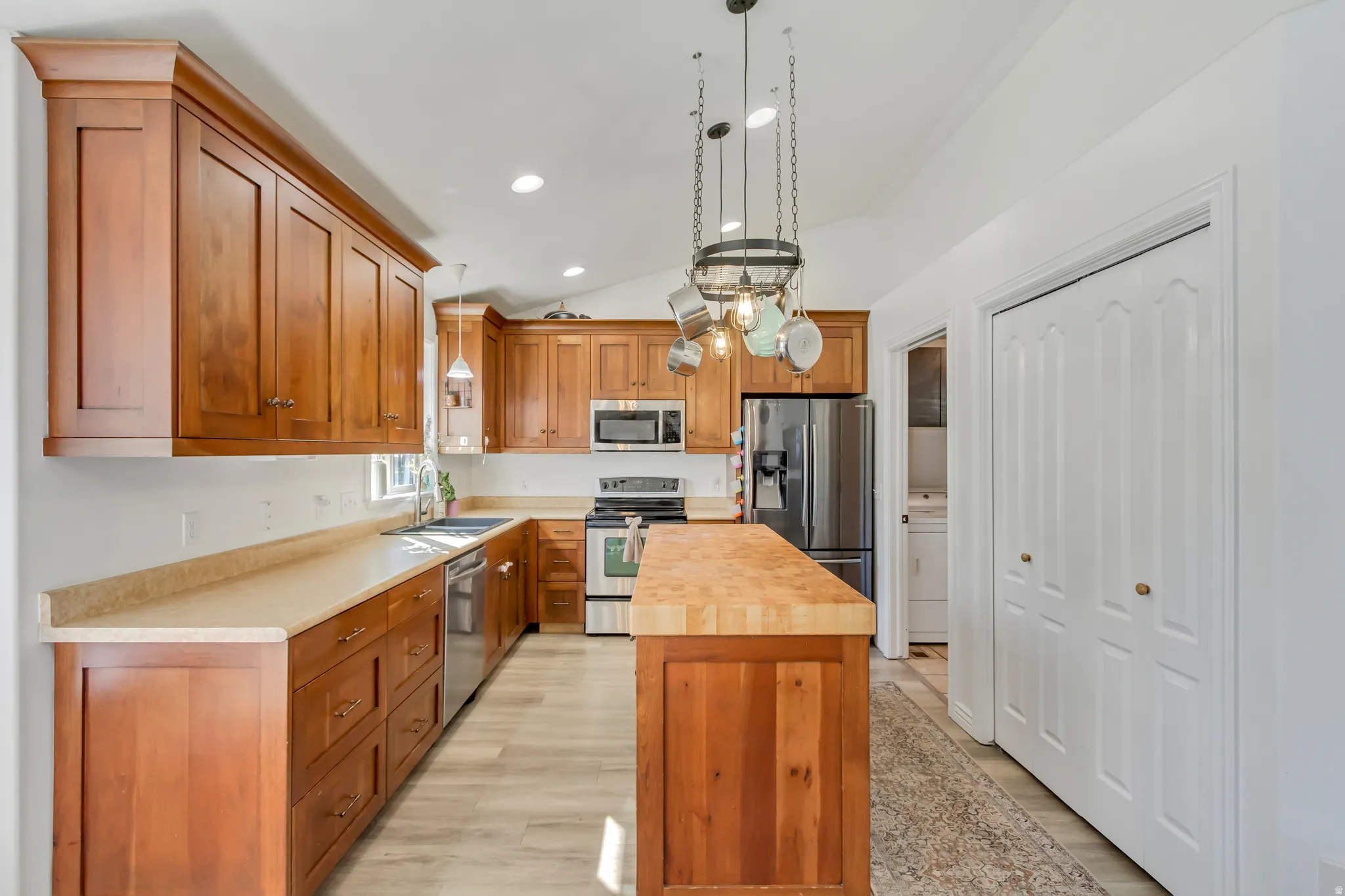 Kitchen featuring wood cabinetry, stainless steel appliances, a center island with a wood countertop, recessed lighting, and wood-finish flooring