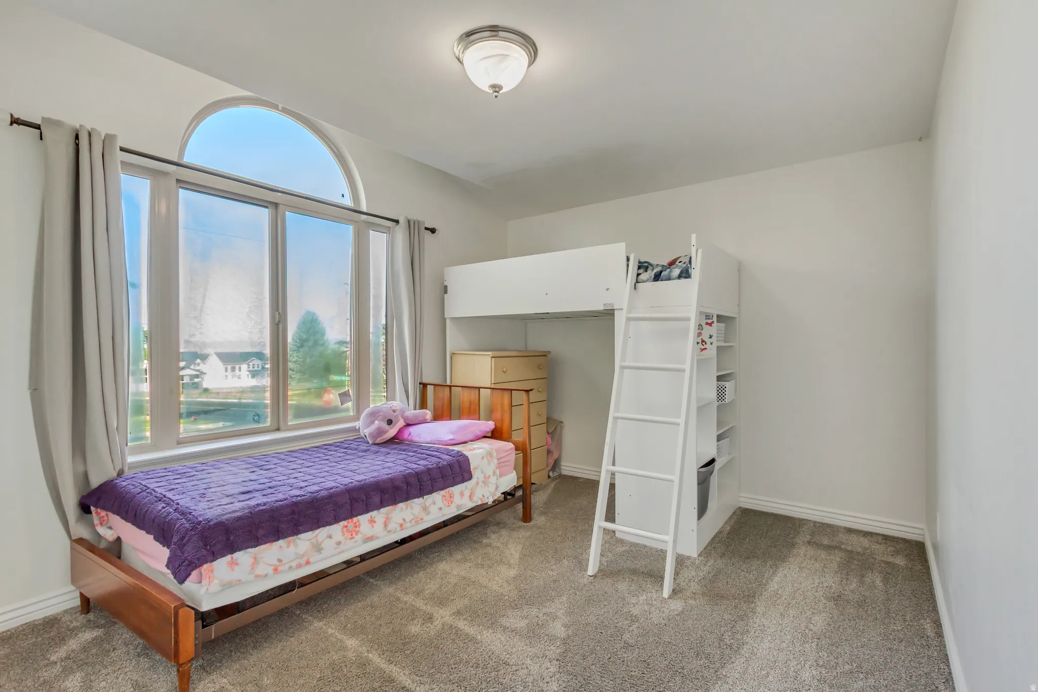 Room featuring a large bay window with an arched transom, light gray wall paint, and gray carpet flooring
