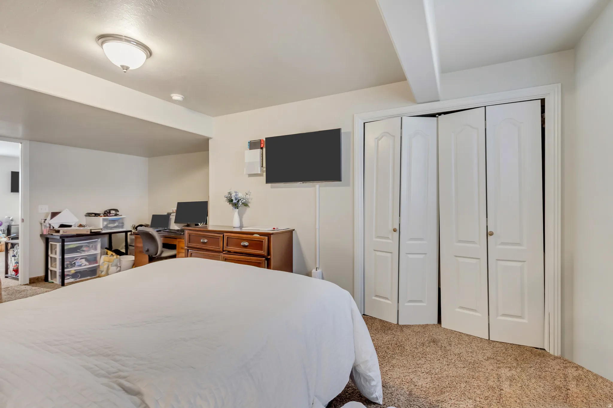 Carpeted bedroom featuring bi-fold closet doors, a flush-mount ceiling light fixture, and a neutral color palette