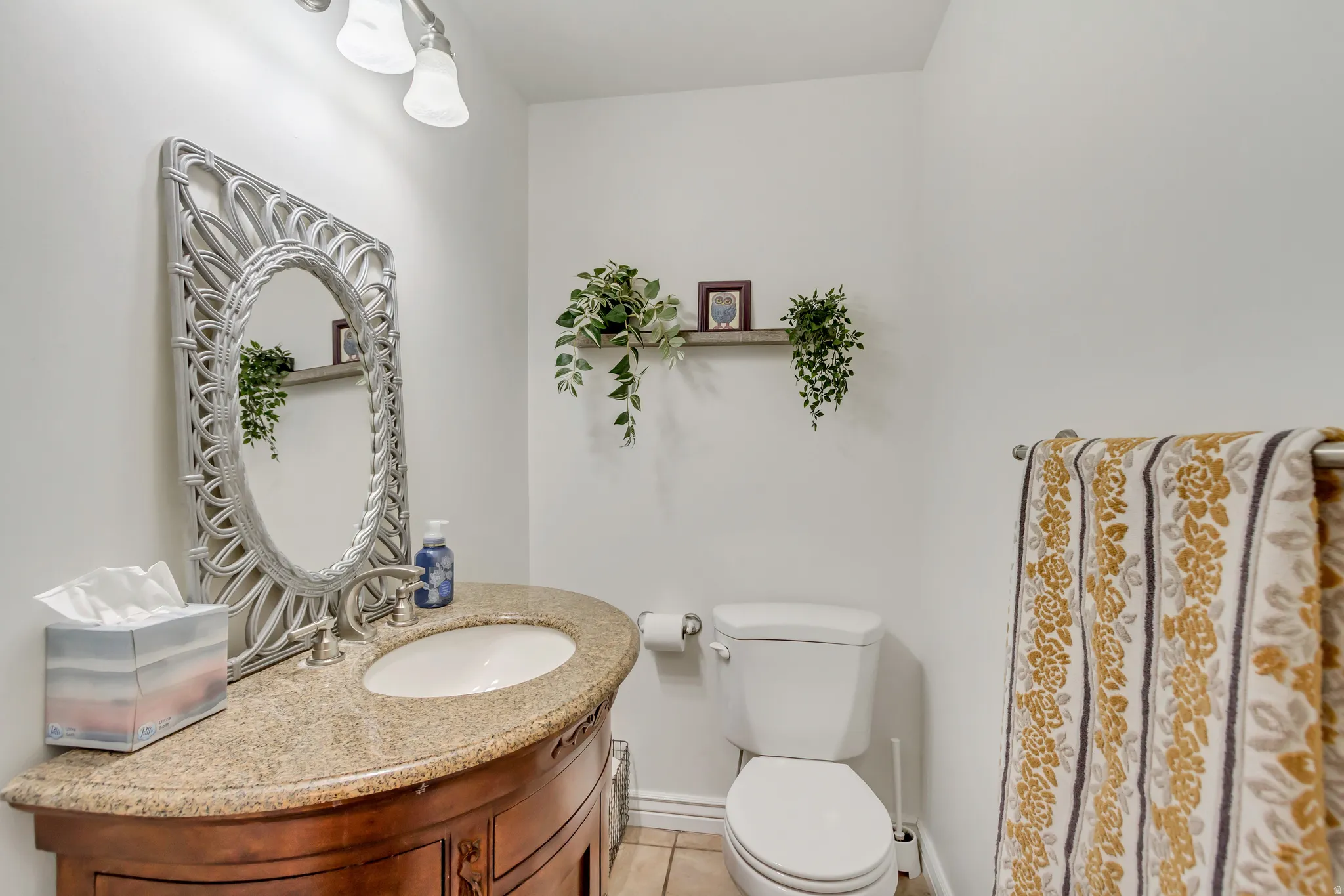 Bathroom featuring a curved wood-finish vanity with an undermount sink, a light-toned countertop, and an ornate silver-framed mirror