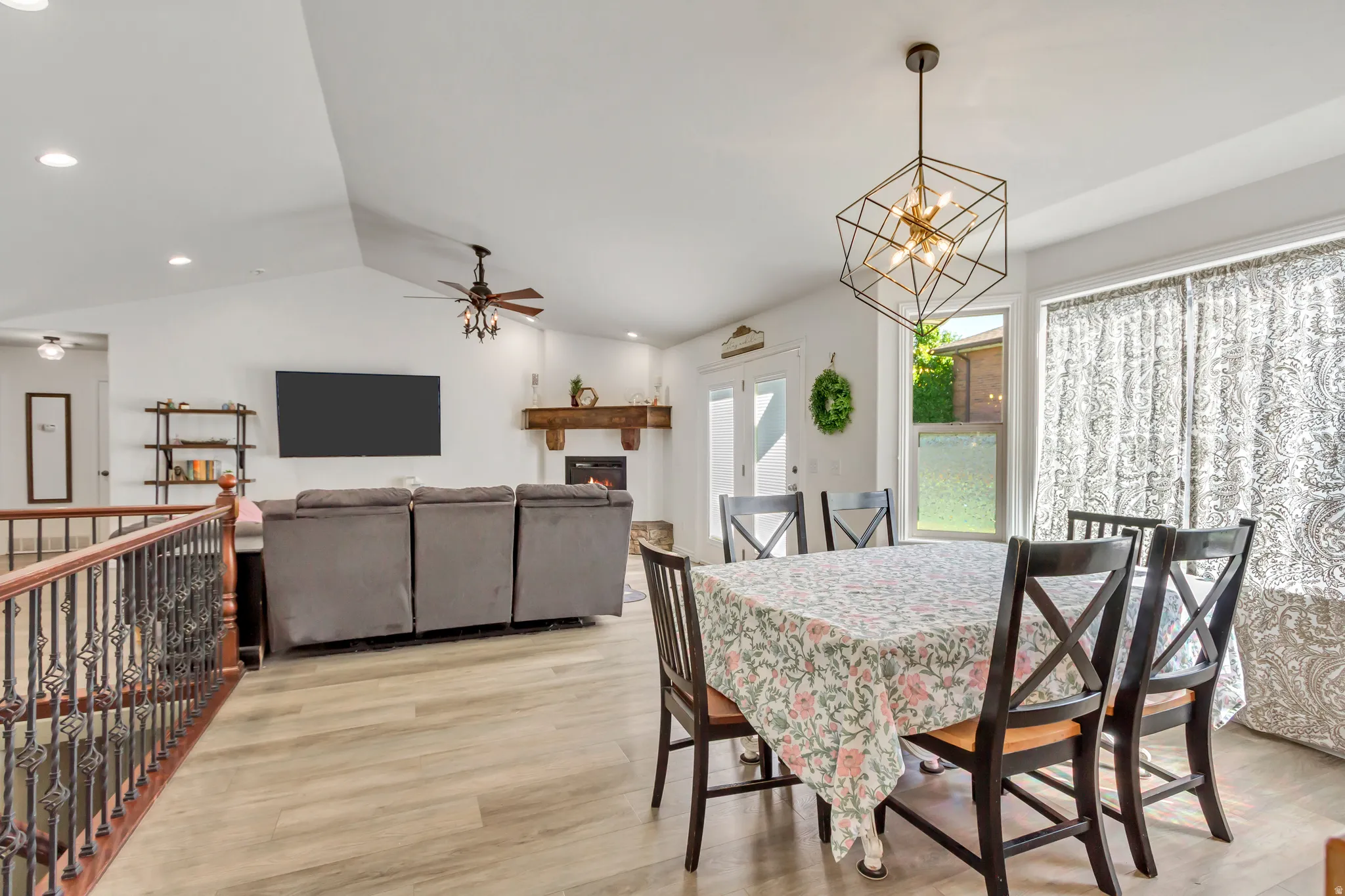 Open-concept living area featuring vaulted ceilings, wood-finish flooring, and a decorative fireplace with a substantial wood mantel