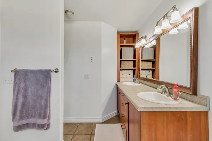 Double vanity with integrated sinks, a wide framed mirror, and warm wood-finish cabinetry