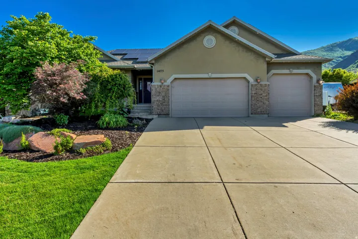 Stucco and brick facade residence featuring a two-car garage, concrete driveway, and front landscaping