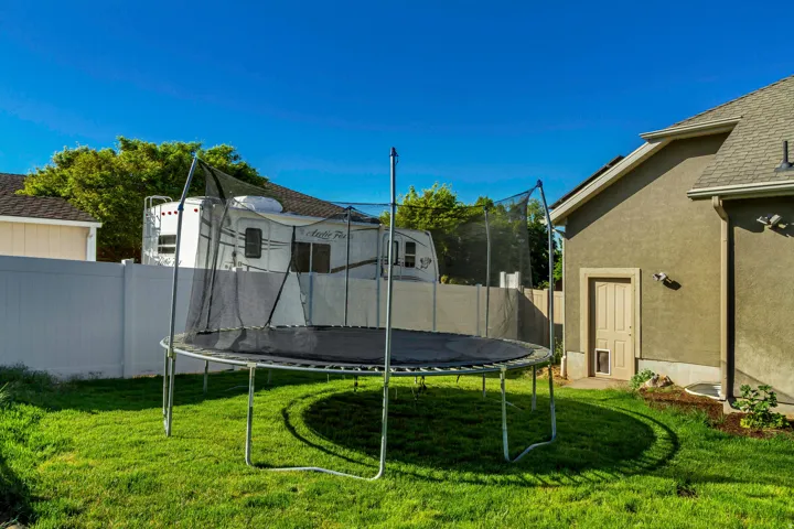 Expansive backyard featuring a lush green lawn, a stucco exterior, and a privacy fence