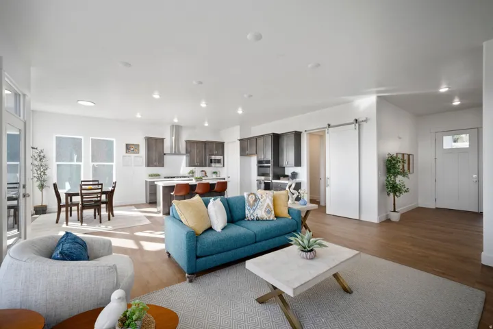 Spacious open-concept living area featuring wood-finish flooring, recessed lighting, and white walls