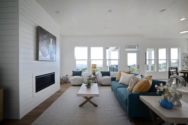 Spacious living area featuring a modern linear fireplace with shiplap-style surround, recessed lighting, wood-finish flooring, multiple expansive windows, and a glass-paned exterior door