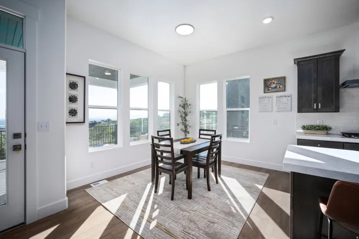 Bright dining area with wood-finish flooring and multiple windows