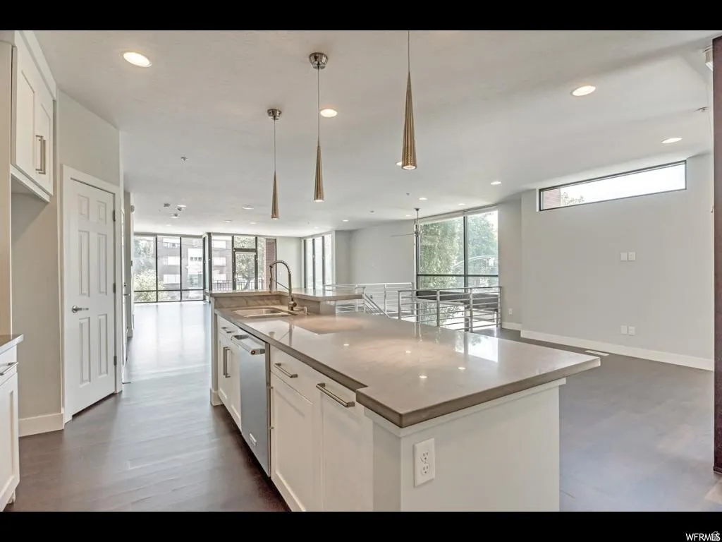 Modern kitchen island featuring a substantial countertop, integrated sink, and stainless steel dishwasher