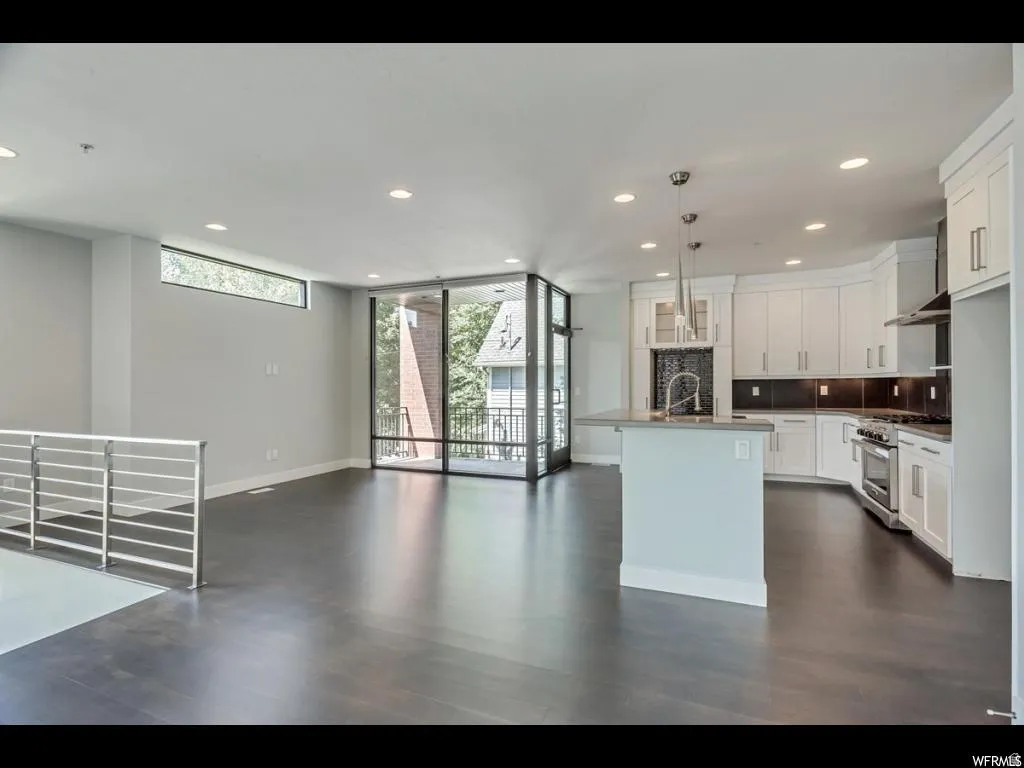 Open-concept living area featuring dark wood-finish flooring, recessed lighting, and a modern kitchen