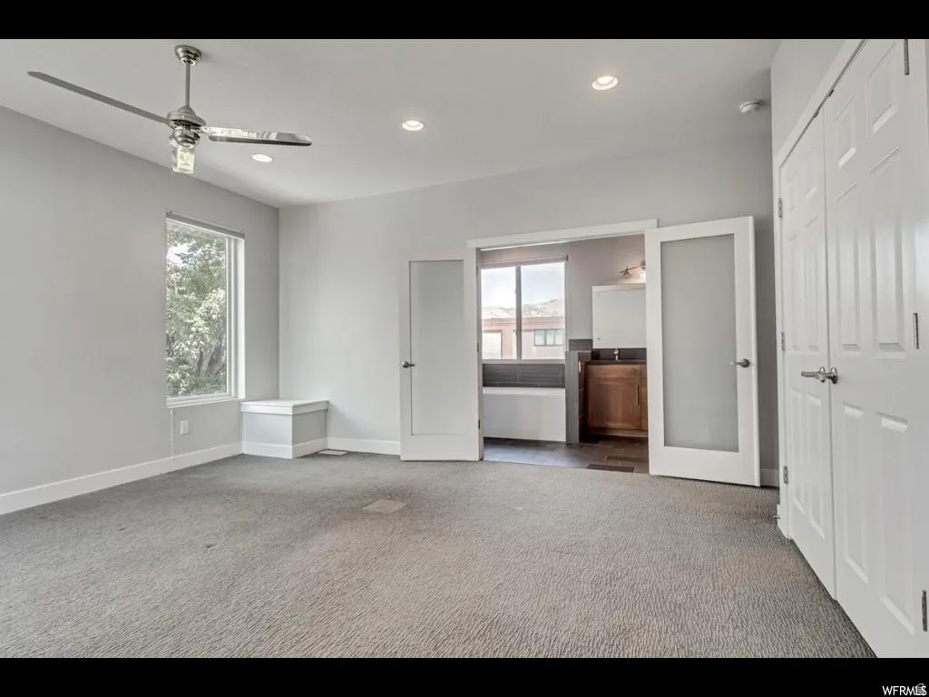 Spacious room featuring light gray walls and plush gray carpeting