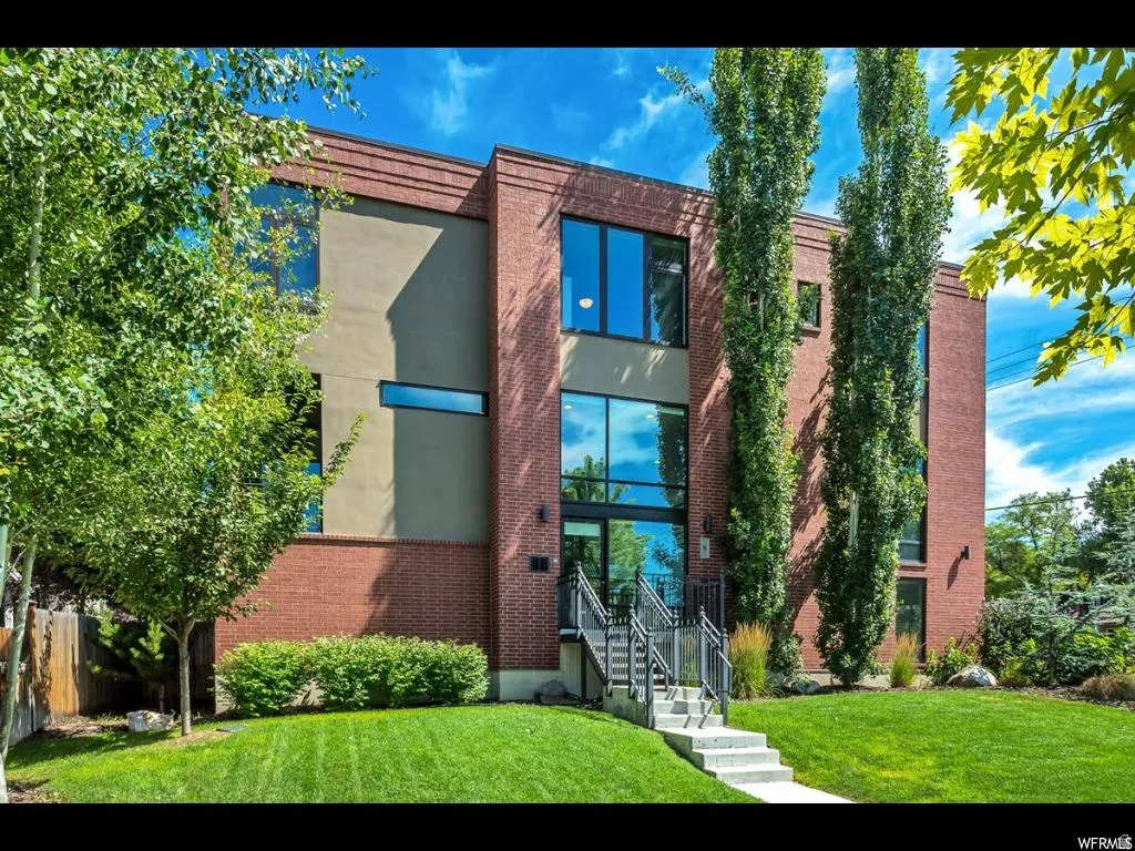 Modern brick and stucco exterior featuring large windows and an inviting concrete staircase with metal railings