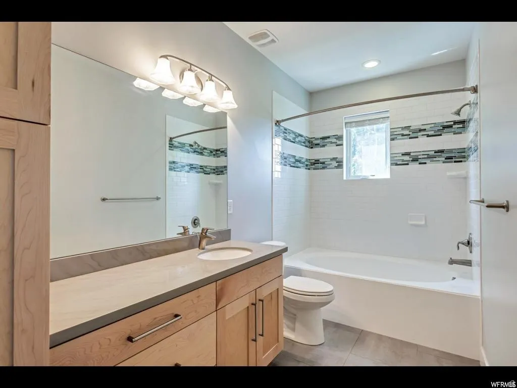 Modern bathroom featuring a light wood-finish vanity with a single sink and a neutral-toned countertop