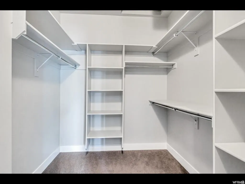 Walk-in closet featuring built-in shelving, multiple hanging rods, and neutral-toned carpeting