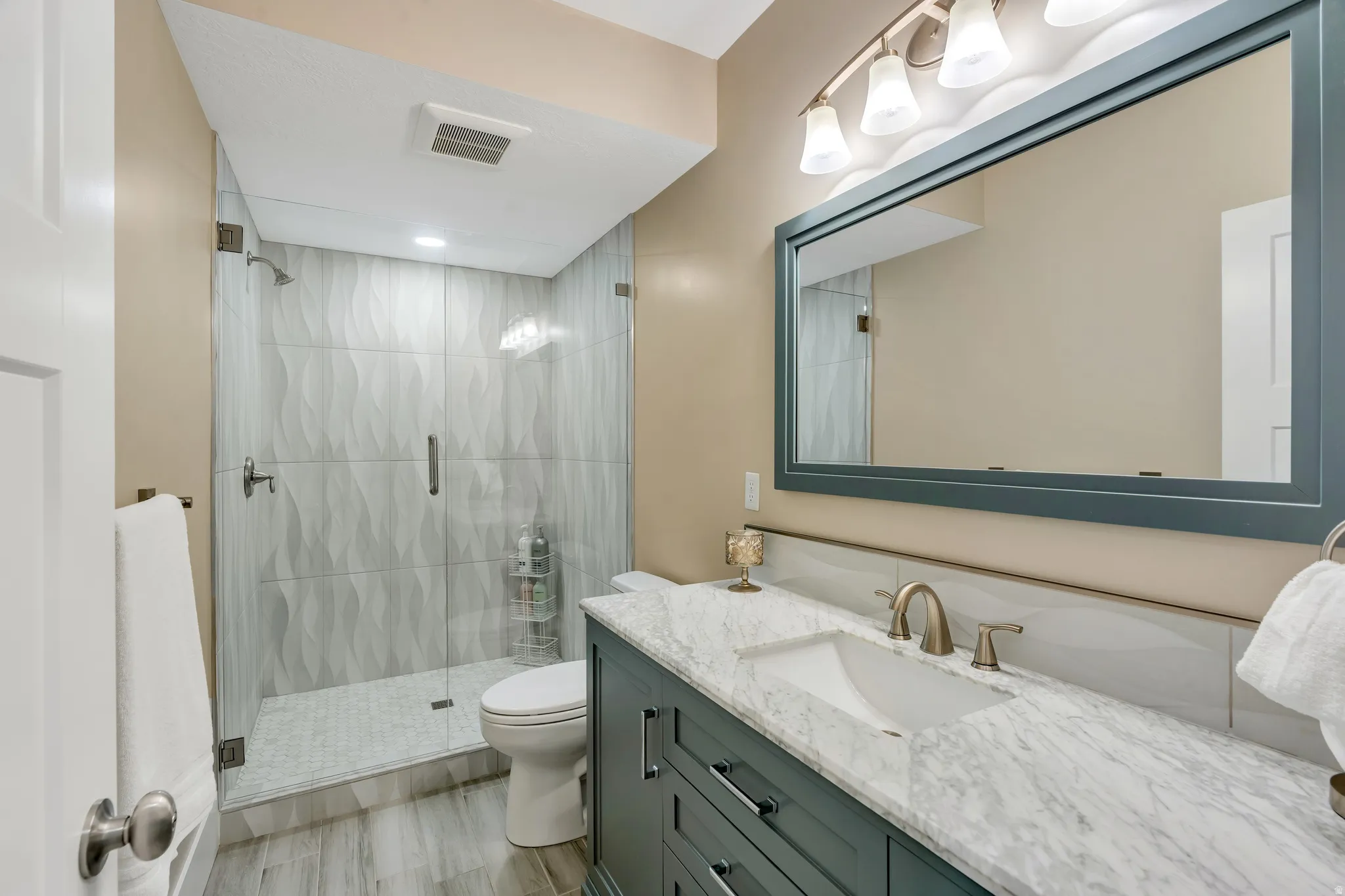 Gorgeous modern updated bathroom featuring marble vanity, and custom euro shower tiles