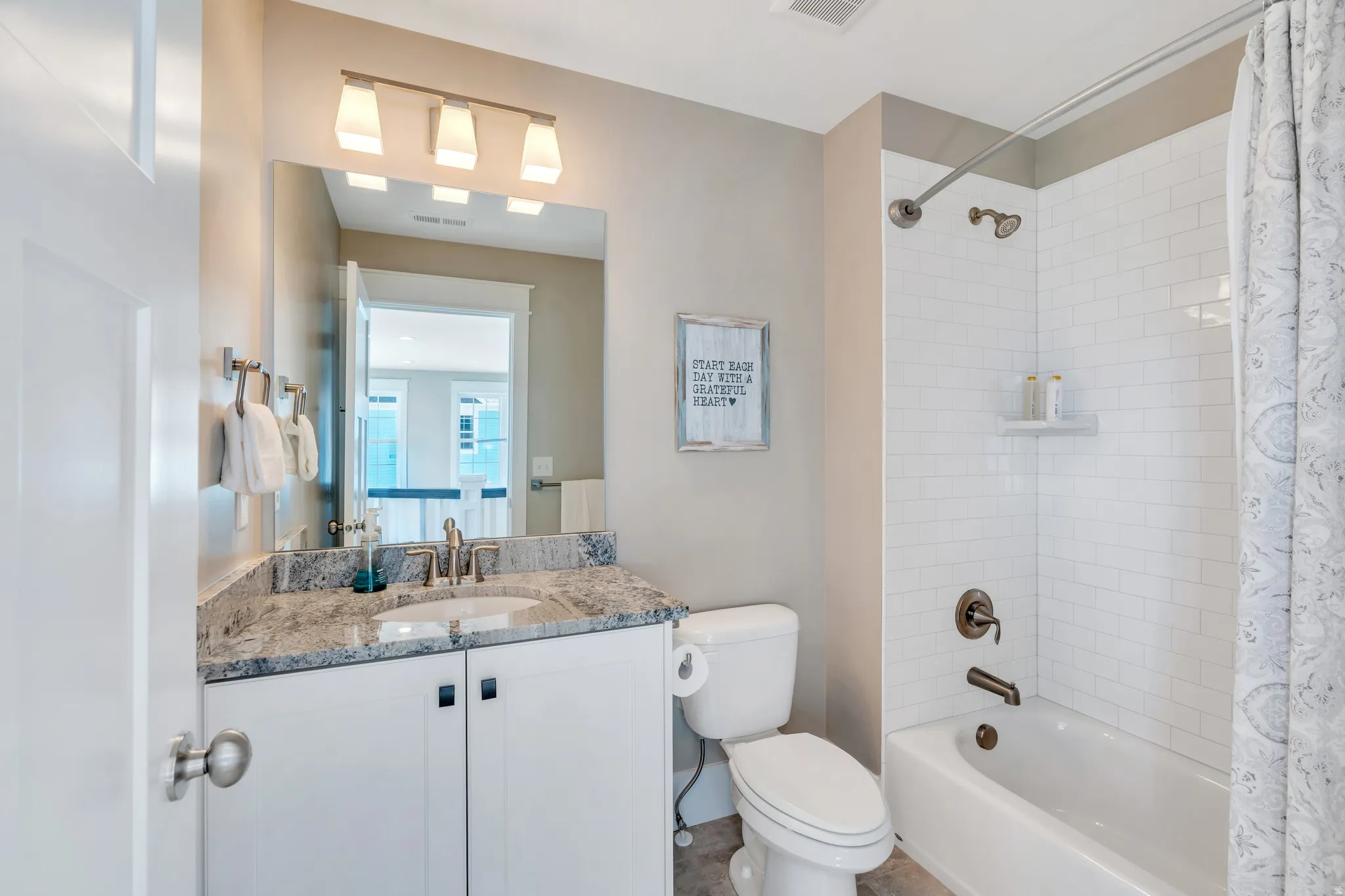 Main upper level bathroom featuring dark granite vanity, brass hardware and spacious tub/shower