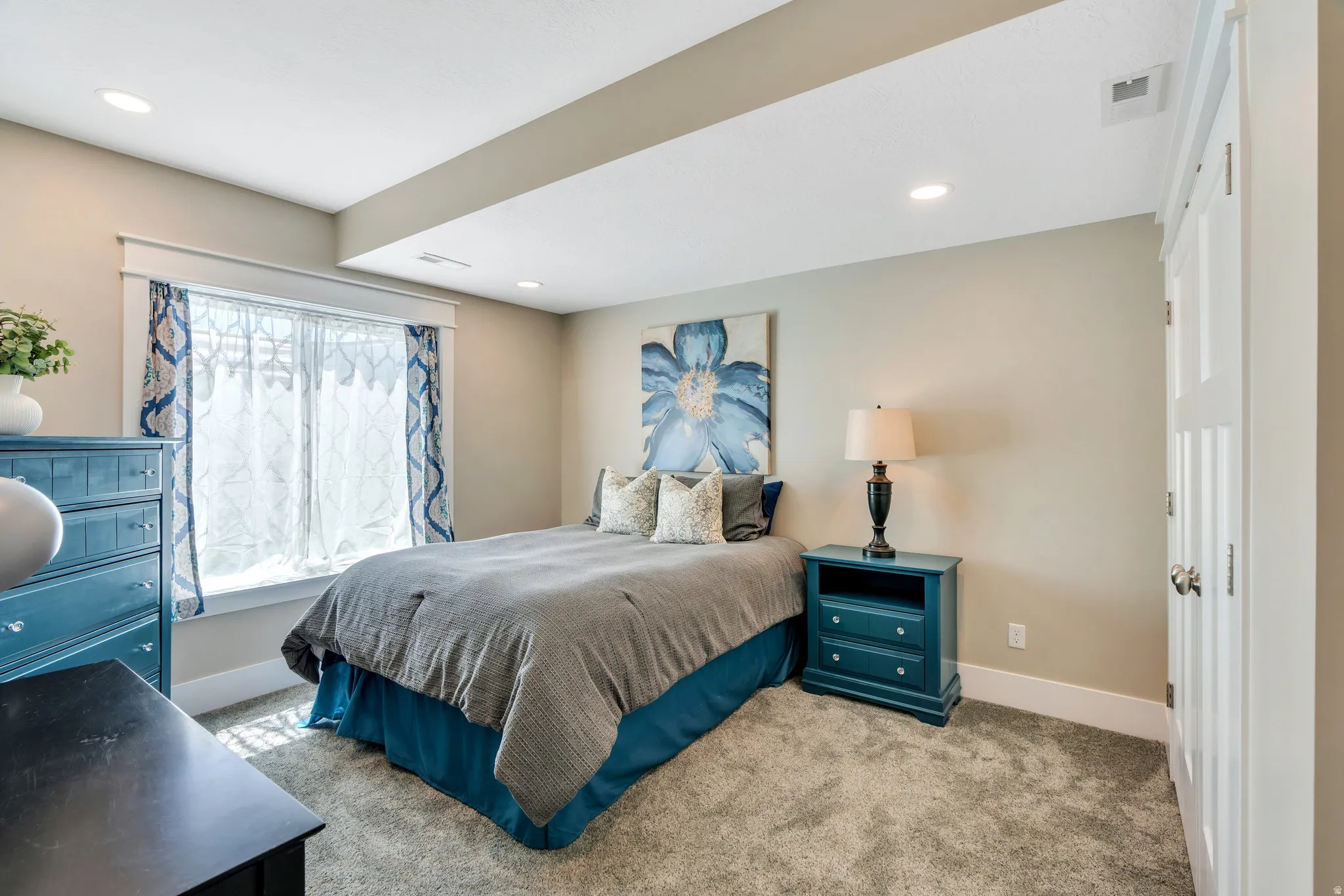 Bright bedroom featuring raised ceilings and double door closet