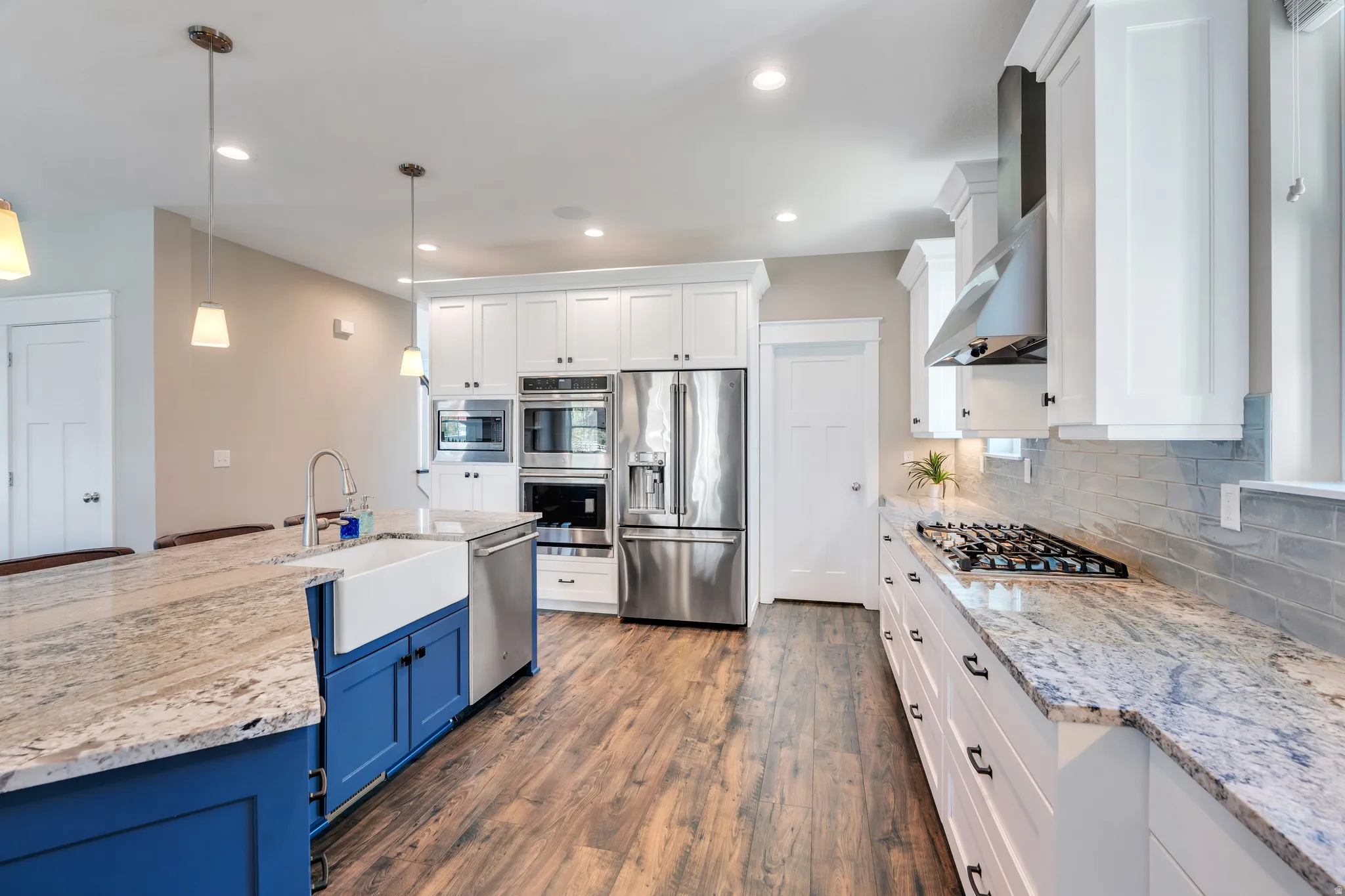 Showcasing the custom backsplash, granite countertops, and stainless-steel appliances and kitchen pantry