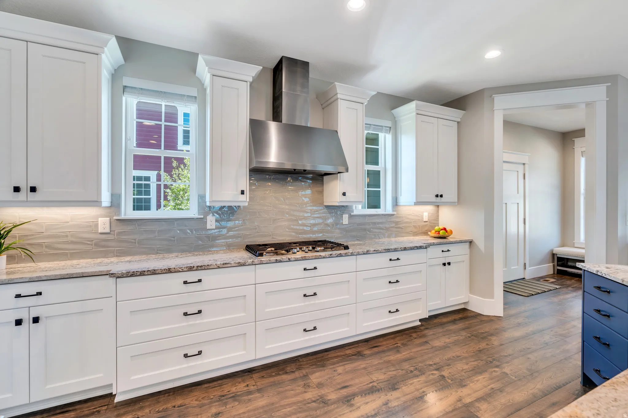 Chef kitchen featuring professional style gas stove, custom backsplash and light granite countertops