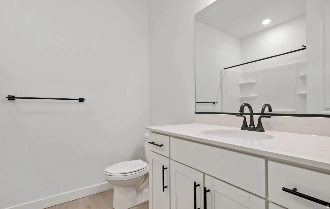 Bathroom featuring a single vanity with a white countertop and undermount sink, matte black faucet and hardware, and recessed lighting