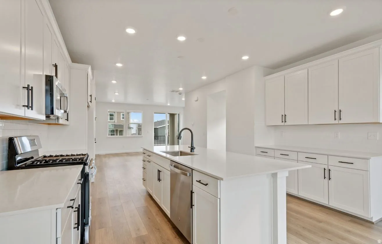 Spacious kitchen featuring white cabinetry, light countertops, wood-finish flooring, recessed lighting, and stainless steel appliances
