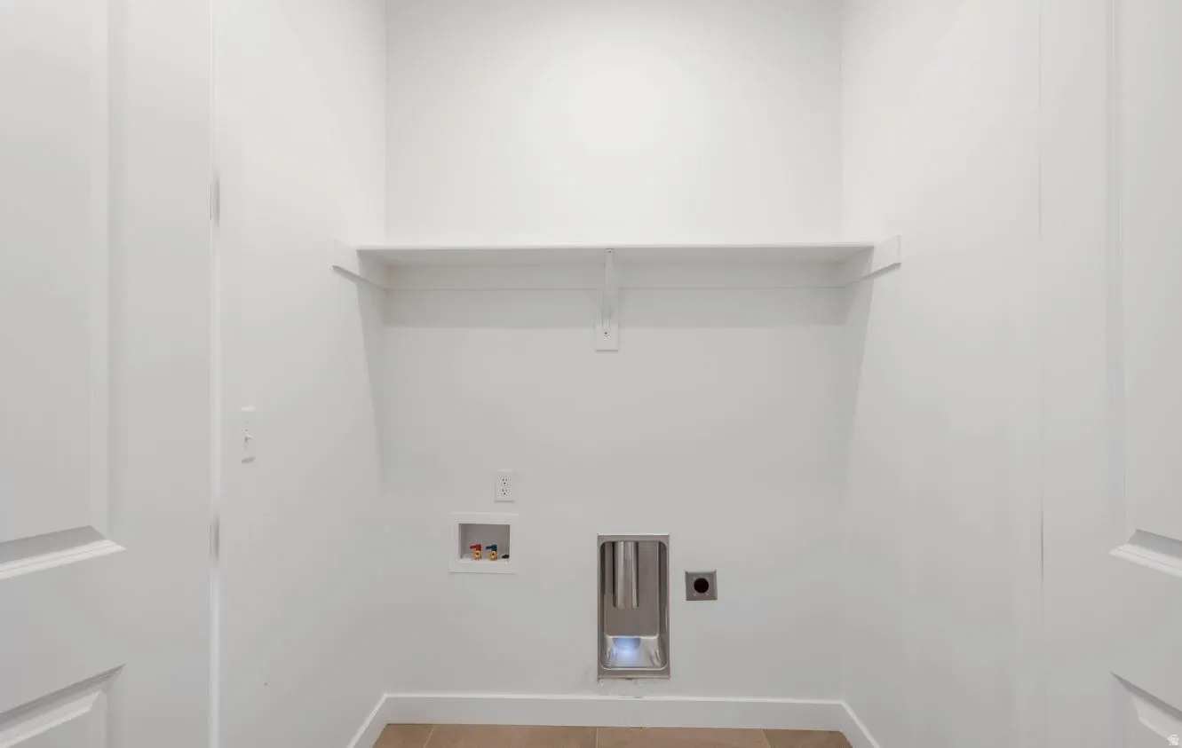 Dedicated utility space featuring a built-in shelf, appliance hookups, and light-toned flooring