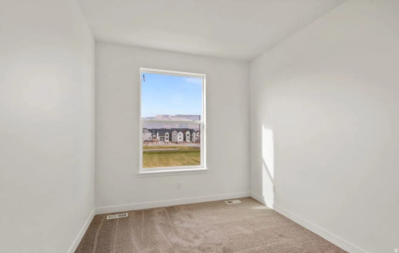 Spacious room featuring a large window, neutral carpeting, white baseboards, and white painted walls