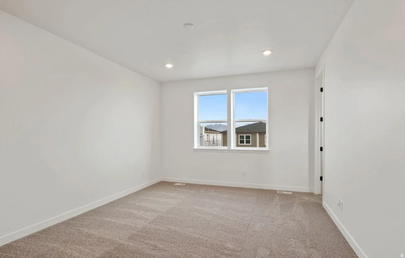 Carpeted interior space featuring dual windows, recessed ceiling lighting, white walls, white trim, and a white door frame
