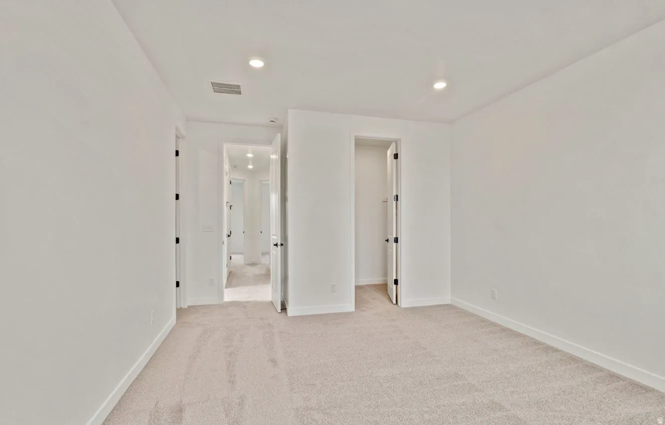 Neutral-toned carpeting defining an interior space with a recessed lighting fixture