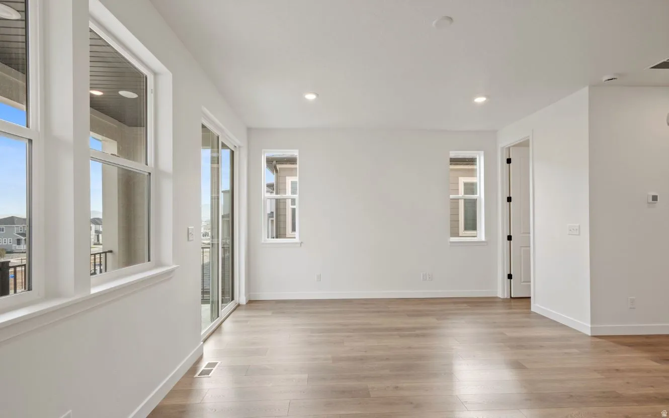 Spacious room featuring wood-finish flooring, recessed lighting, and multiple windows