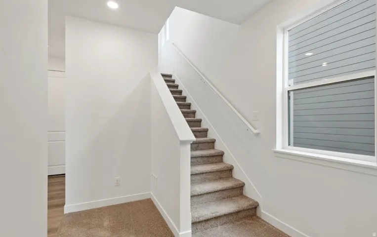 Carpeted staircase with white balustrade and handrail