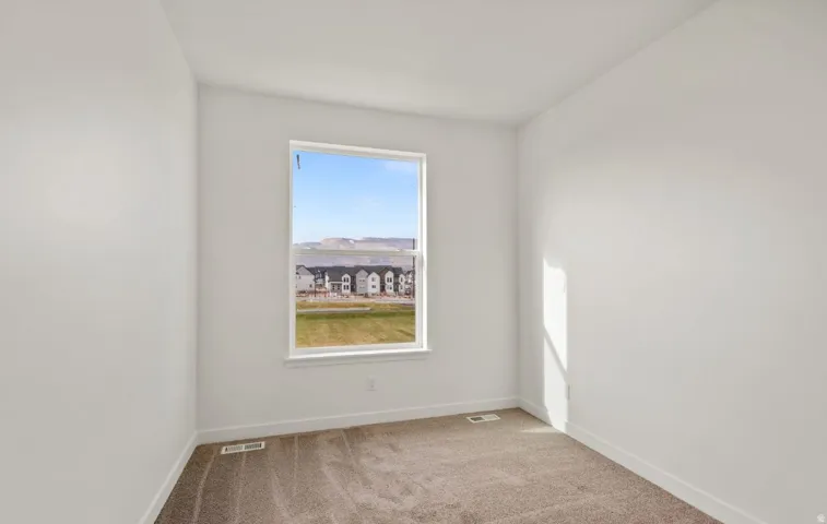 Spacious room featuring a large window, neutral carpeting, white baseboards, and white painted walls