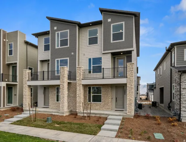 Contemporary multi-level townhome featuring a stone facade and contrasting siding