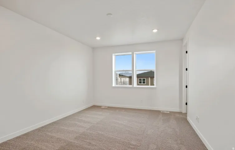 Carpeted interior space featuring dual windows, recessed ceiling lighting, white walls, white trim, and a white door frame