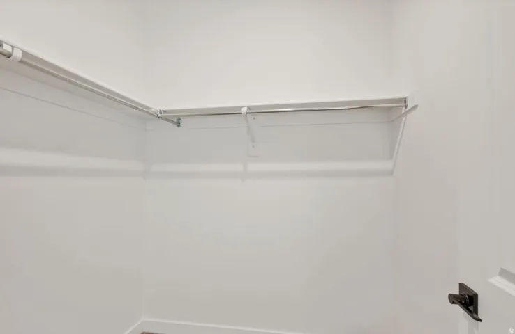 White interior closet featuring a garment rod, upper shelf, and painted walls