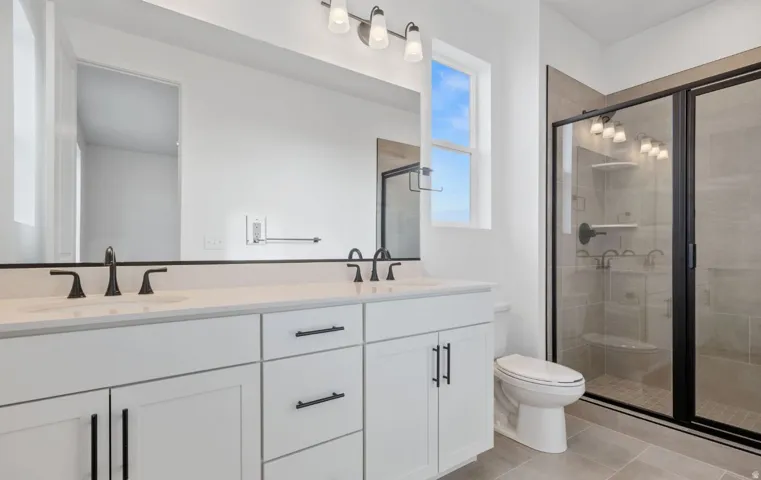 Double vanity with white cabinetry, matte black hardware, and an expansive mirror