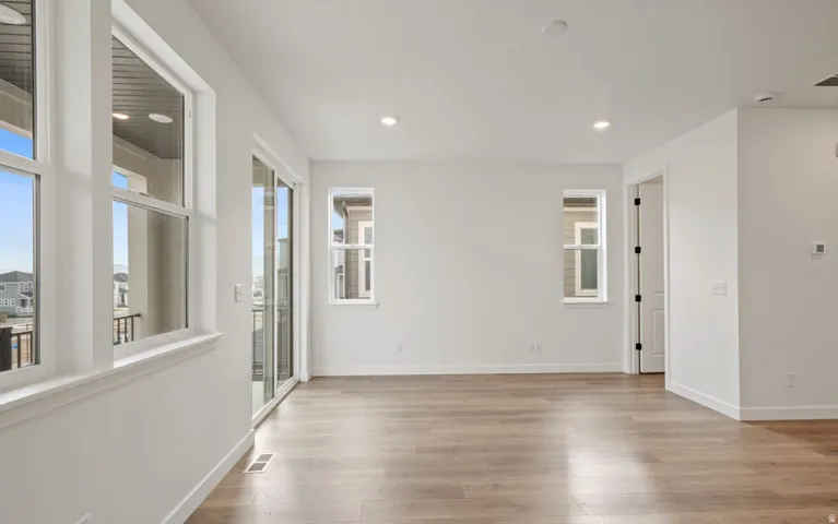 Spacious room featuring wood-finish flooring, recessed lighting, and multiple windows