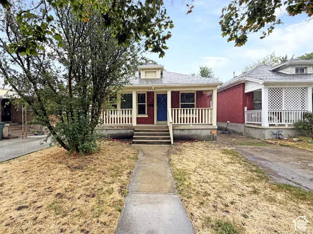 Red exterior with a front porch, white railings, and a blue entry door