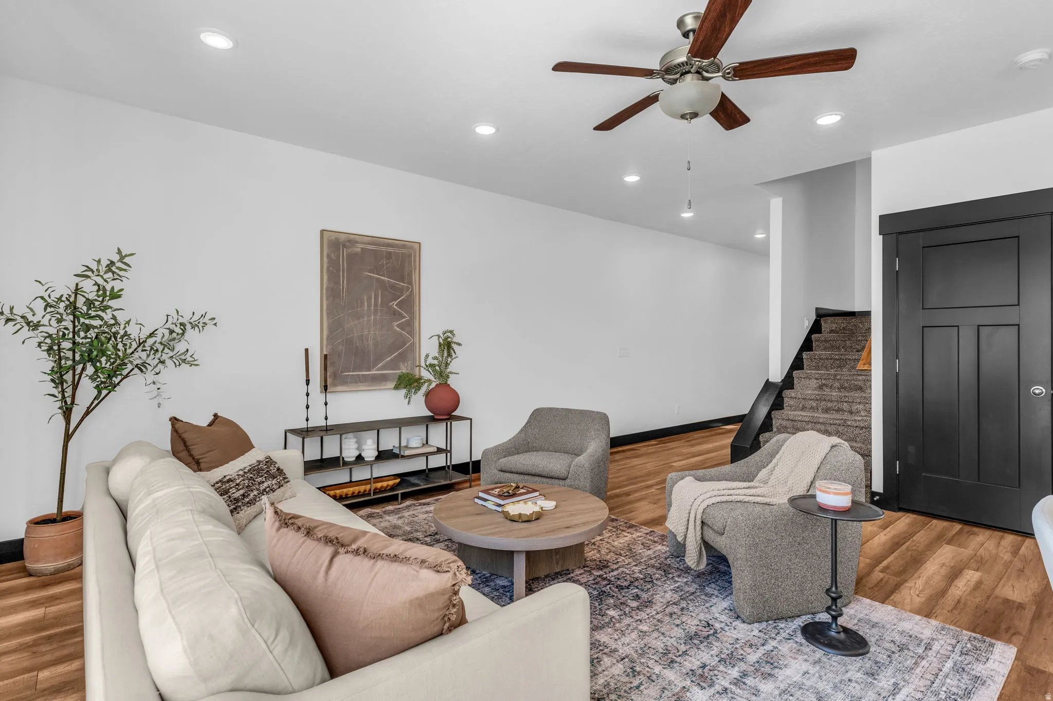 Living area featuring wood-finish flooring, recessed lighting, and a ceiling fan with wood-tone blades
