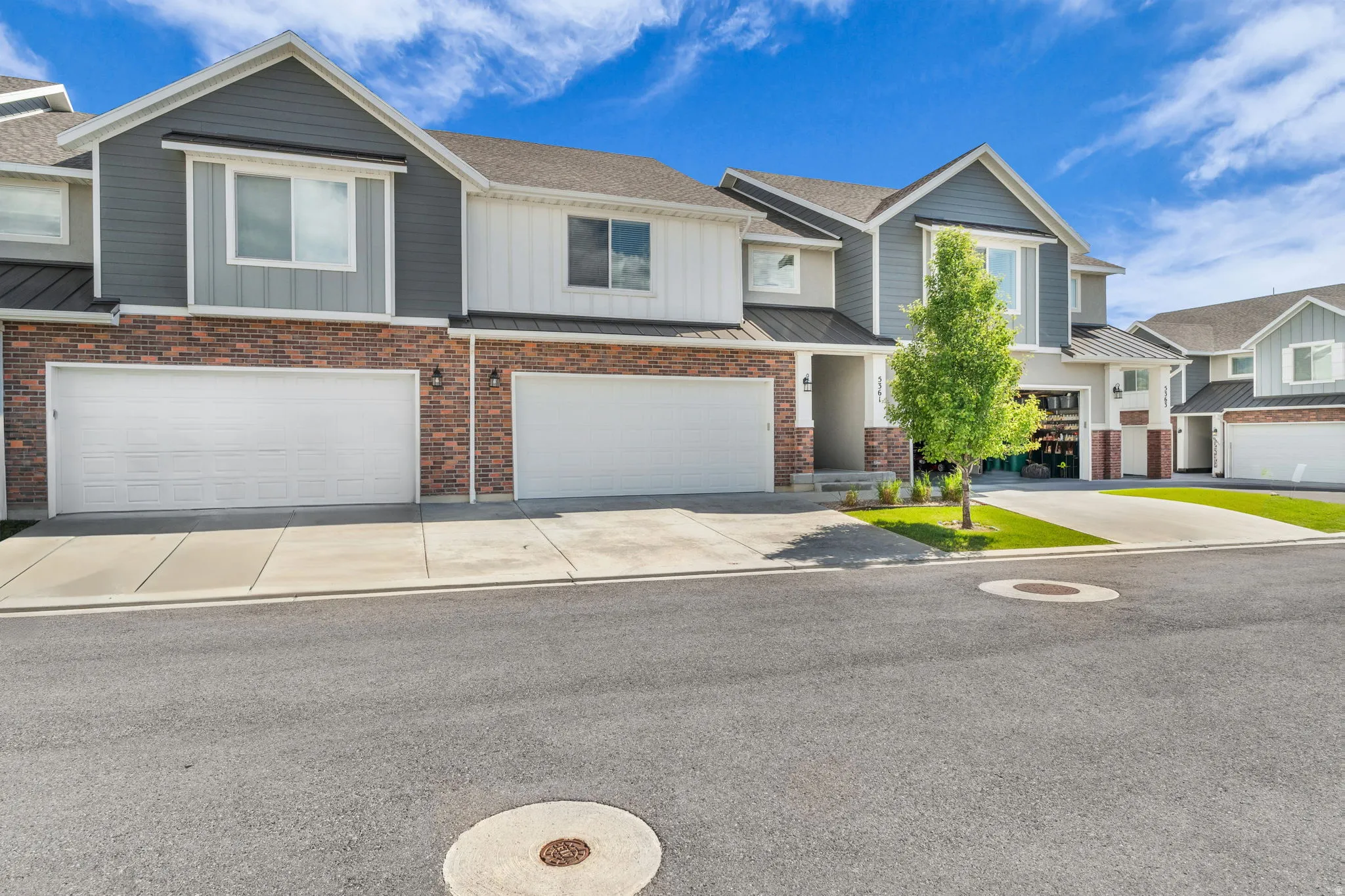 Contemporary townhome featuring a mix of brick and horizontal siding, multiple two-car garages, and concrete driveways